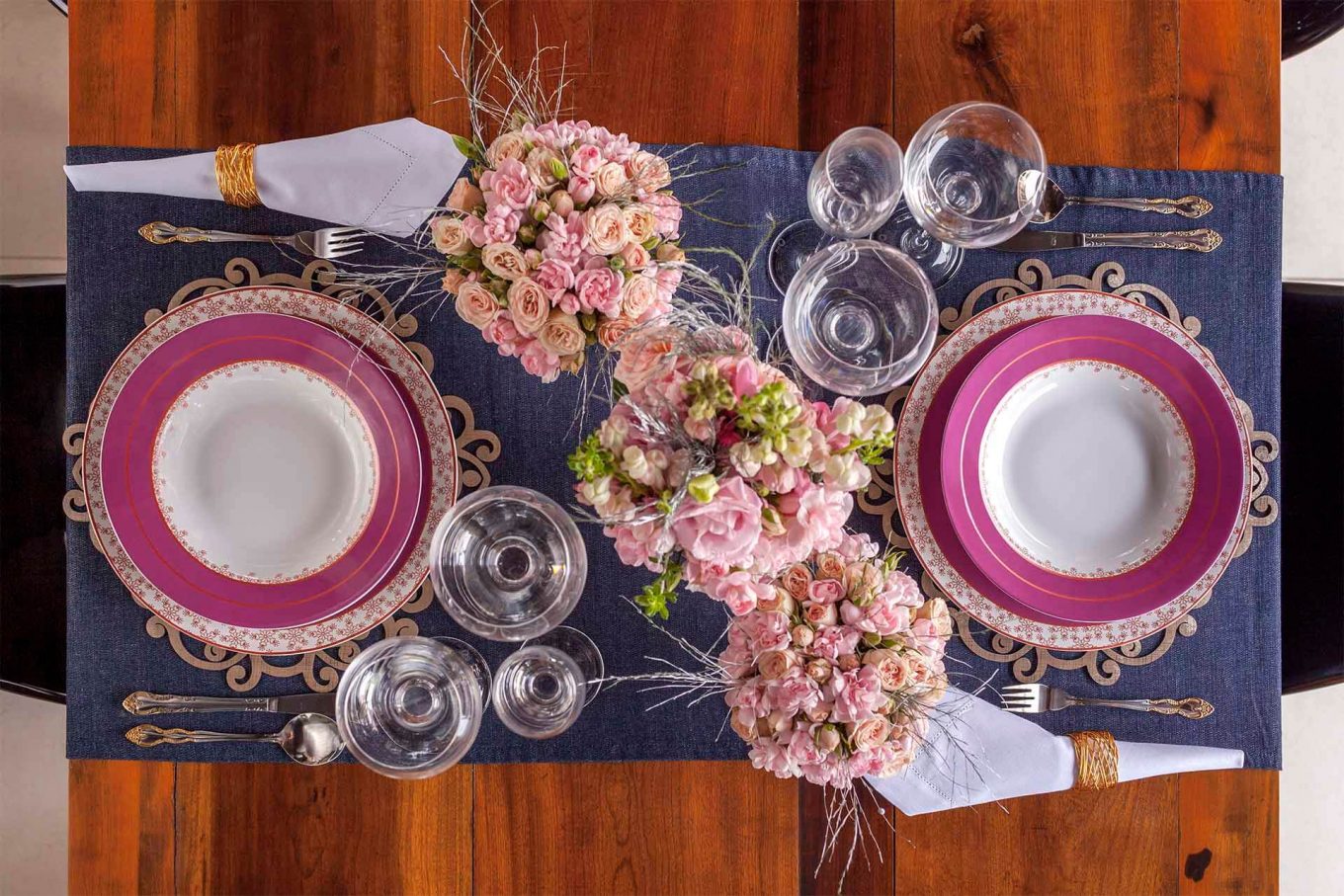 Uma mesa que une elegância, garantida pelo guardanapo de linho branco envolto em dourado, e descontração, pela escolha do jeans. Foto: Raphael Günther/Bespoke Content. Imagem: Uma mesa que une elegância, garantida pelo guardanapo de linho branco envolto em dourado, e descontração, pela escolha do jeans. Foto: Raphael Günther/Bespoke Content.