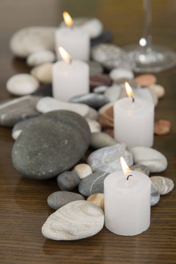 Para compor o centro de mesa, espalhe seixos de vários tamanhos, em tons de cinza, e algumas velas brancas, largas e baixas. Fotos: Cacá Bratke Imagem: Para compor o centro de mesa, espalhe seixos de vários tamanhos, em tons de cinza, e algumas velas brancas, largas e baixas. Fotos: Cacá Bratke