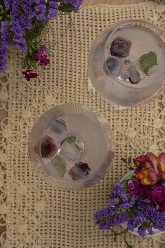 foto feita de cima mostra duas taças de cristal com água e cubos de gelo saborizado.