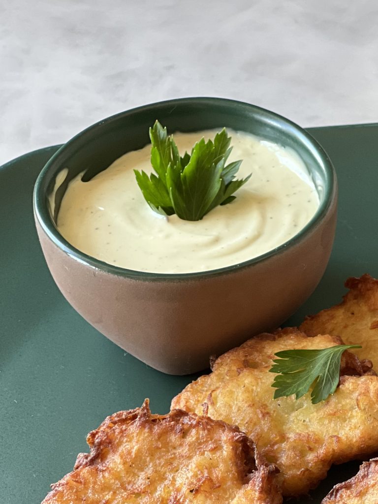 Imagem: latkes com molho de queijo servidos em travessa verde.