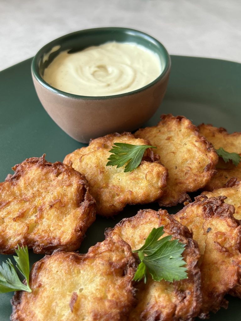 Imagem: latkes com molho de queijo servidos em travessa verde.