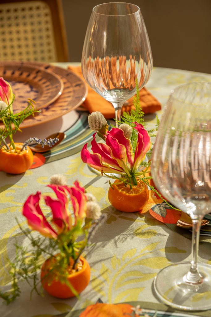 Imagem: mesa posta com pratos laranja e toalha verde.