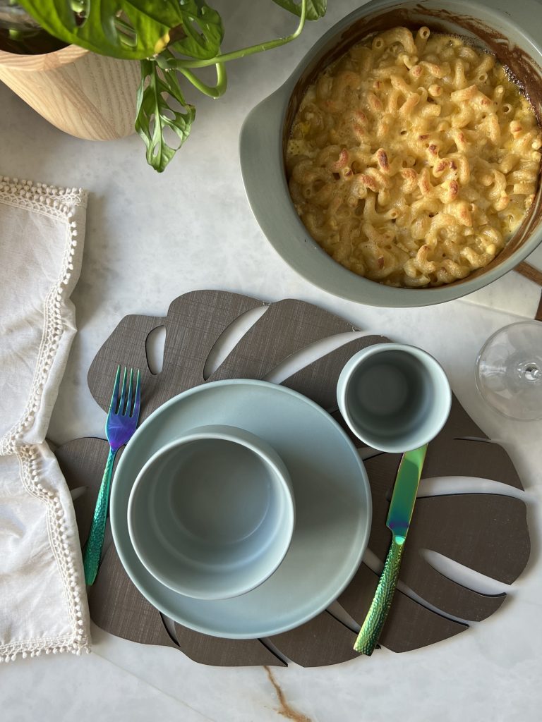 Imagem: louças verdes de cerâmica e panela com mac n cheese. 