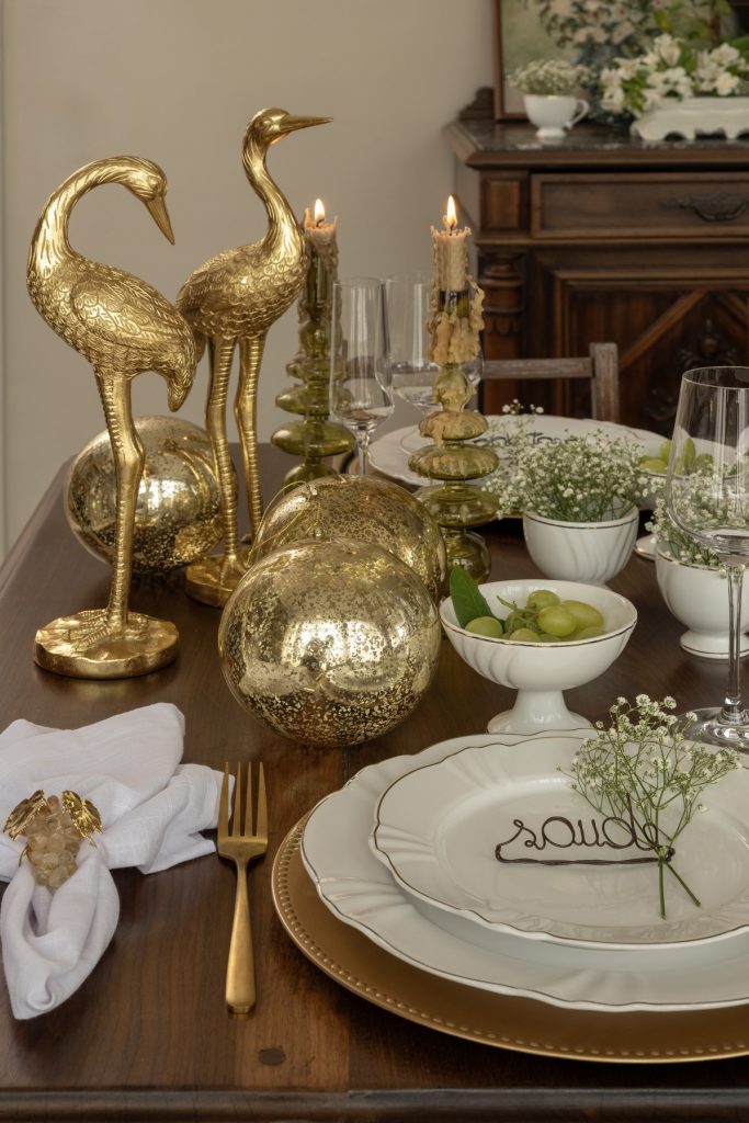 Na ponta dessa mesa de Ano Novo simples e impactante, vemos duas esculturas douradas em forma de garça, três bolas douradas e dois castiçais com velas acesas. 